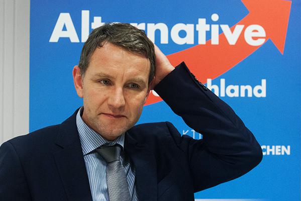Björn Höcke vor einem AfD-Hintergrund, eine Hand am Hinterkopf