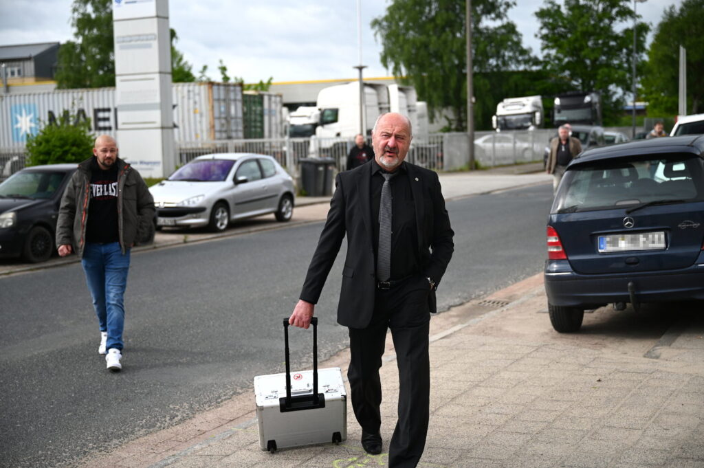 Thomas Jürgewitz in schwarzem Anzug und mit Rollkoffer in Bremen-Mahndorf.