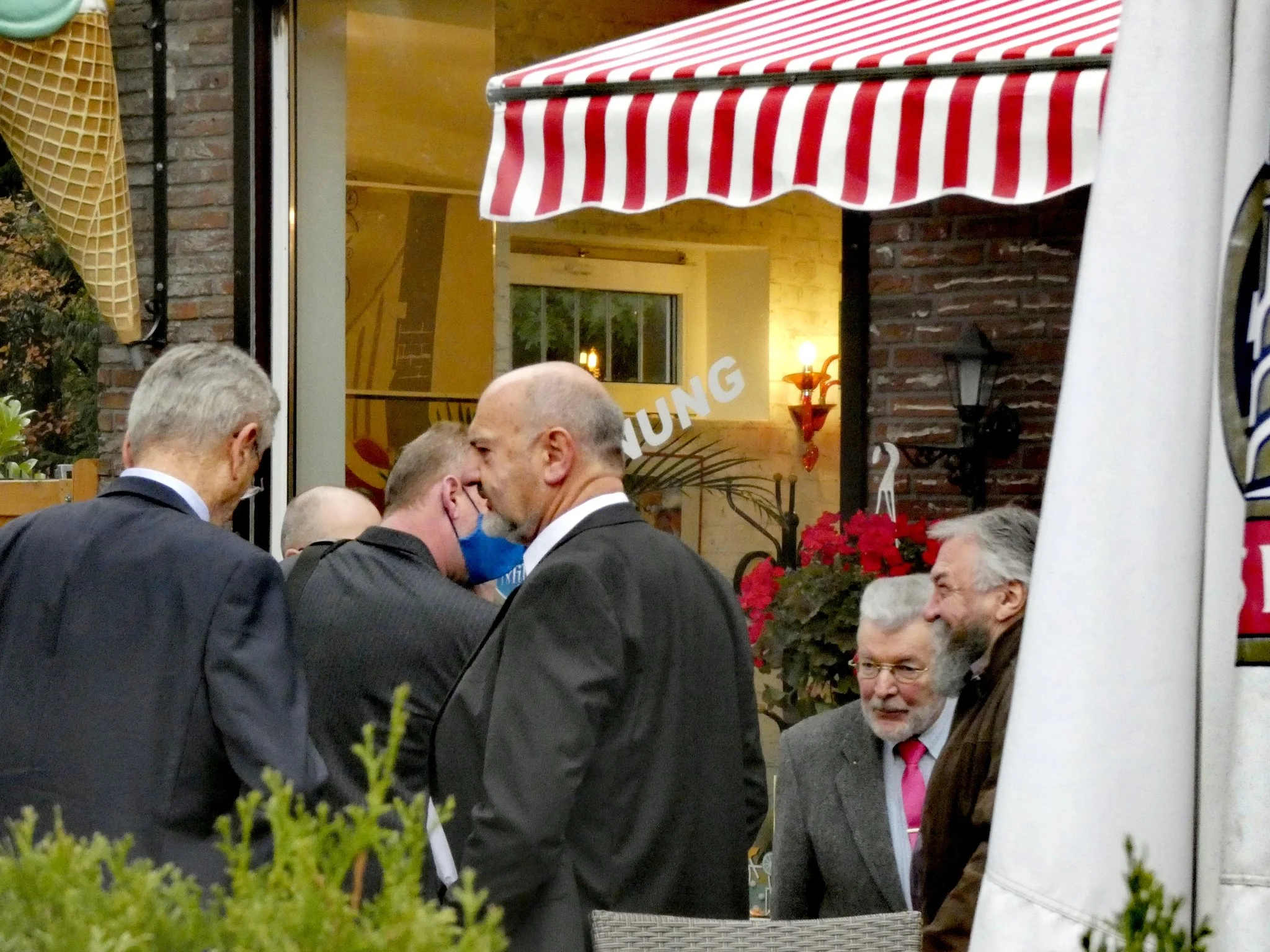 Thomas Jürgewitz steht in der Bildmitte vor dem Restaurant, umgeben von weiteren Personen.