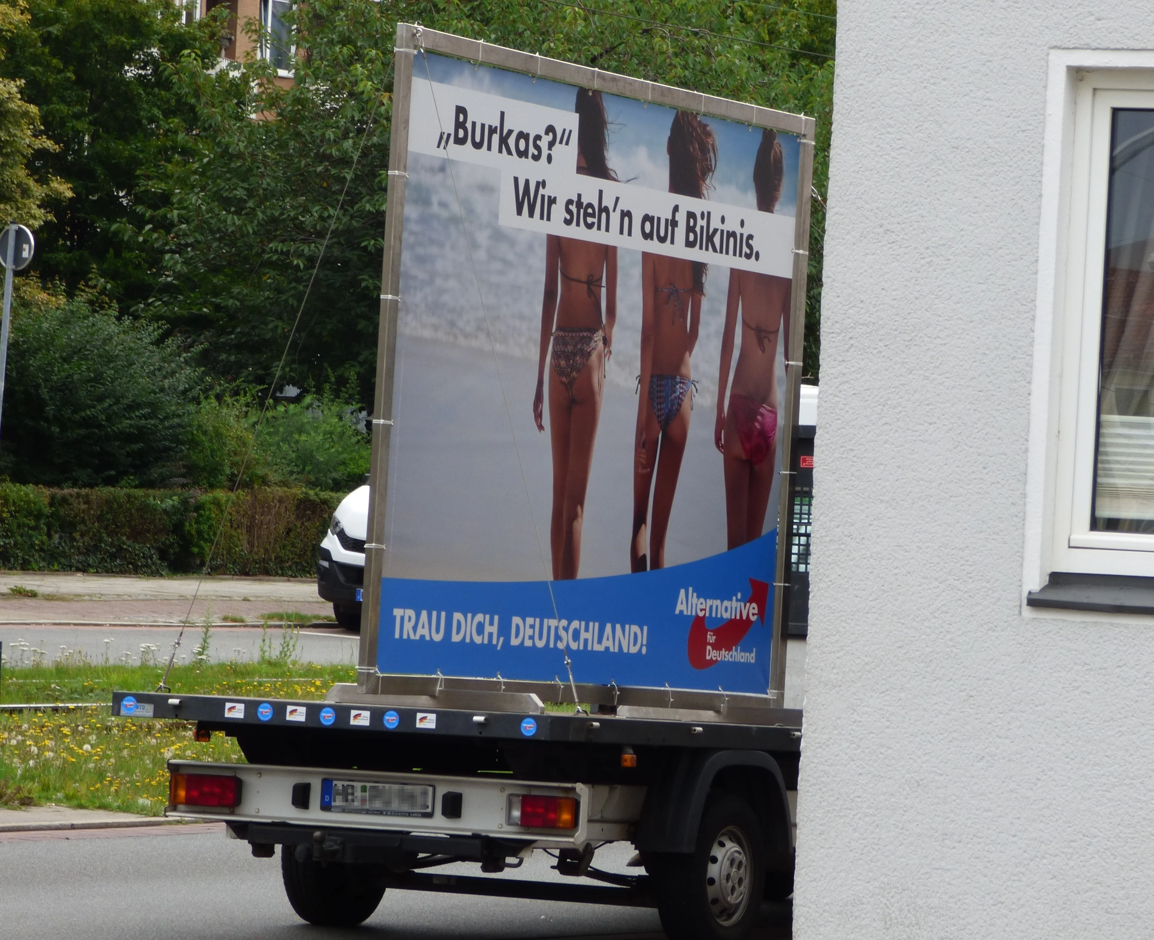 AfD-Plakat auf dem Heck eines Transporters: drei Frauen in Bikinis von hinten und ein gegen Burkas gerichteter Slogan.