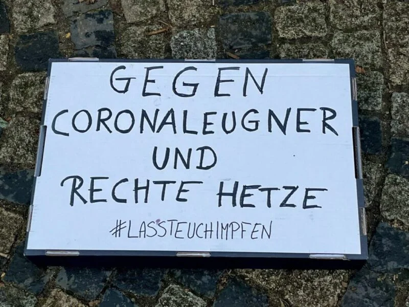 Protestschild mit der Aufschrift Gegen Coronaleugner und rechte Hetze sowie Lasst euch impfen.