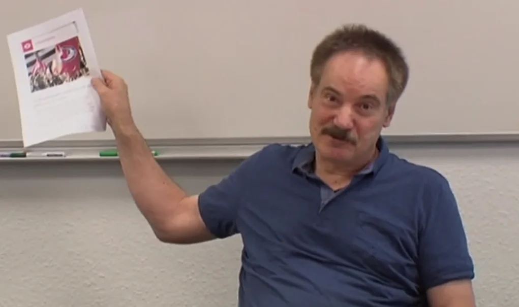 Gerald Höns hält während der Waller Beiratssitzung am 13. September 2018 ein bedrucktes Blatt hoch. Screenshot: Radio Bremen.