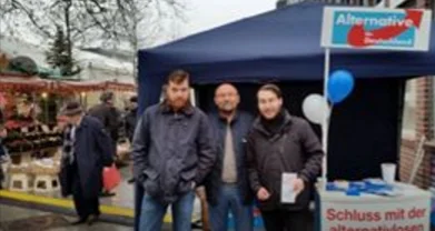 Drei Männer vor einem blauen AfD-Stand auf einem Marktplatz. Die Bildunterschrift benennt die dokumentierten Personen.