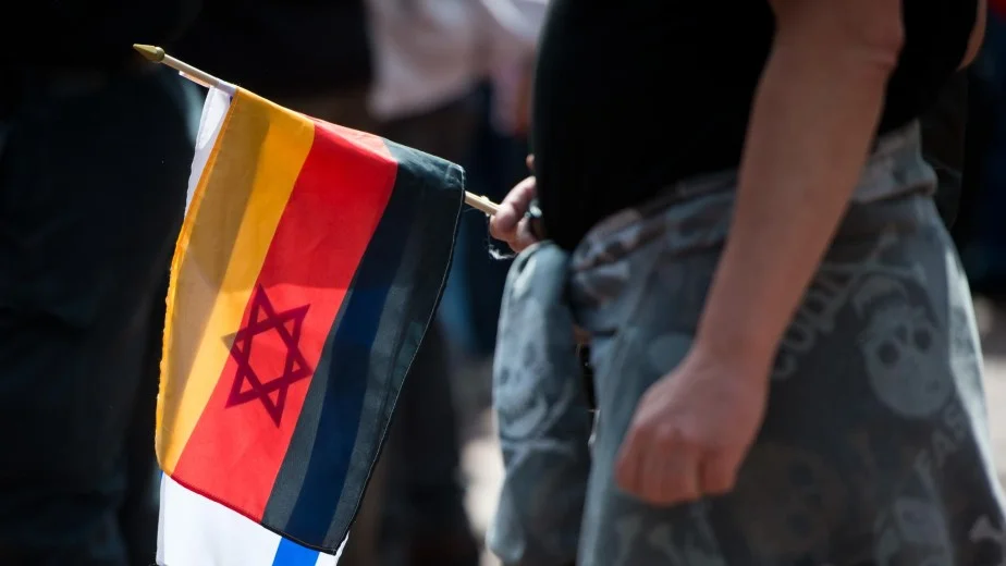 Person bei einer Pegida-Veranstaltung mit einer Deutschlandfahne und einer Israelfahne. Foto: Daniel Naupold/dpa.