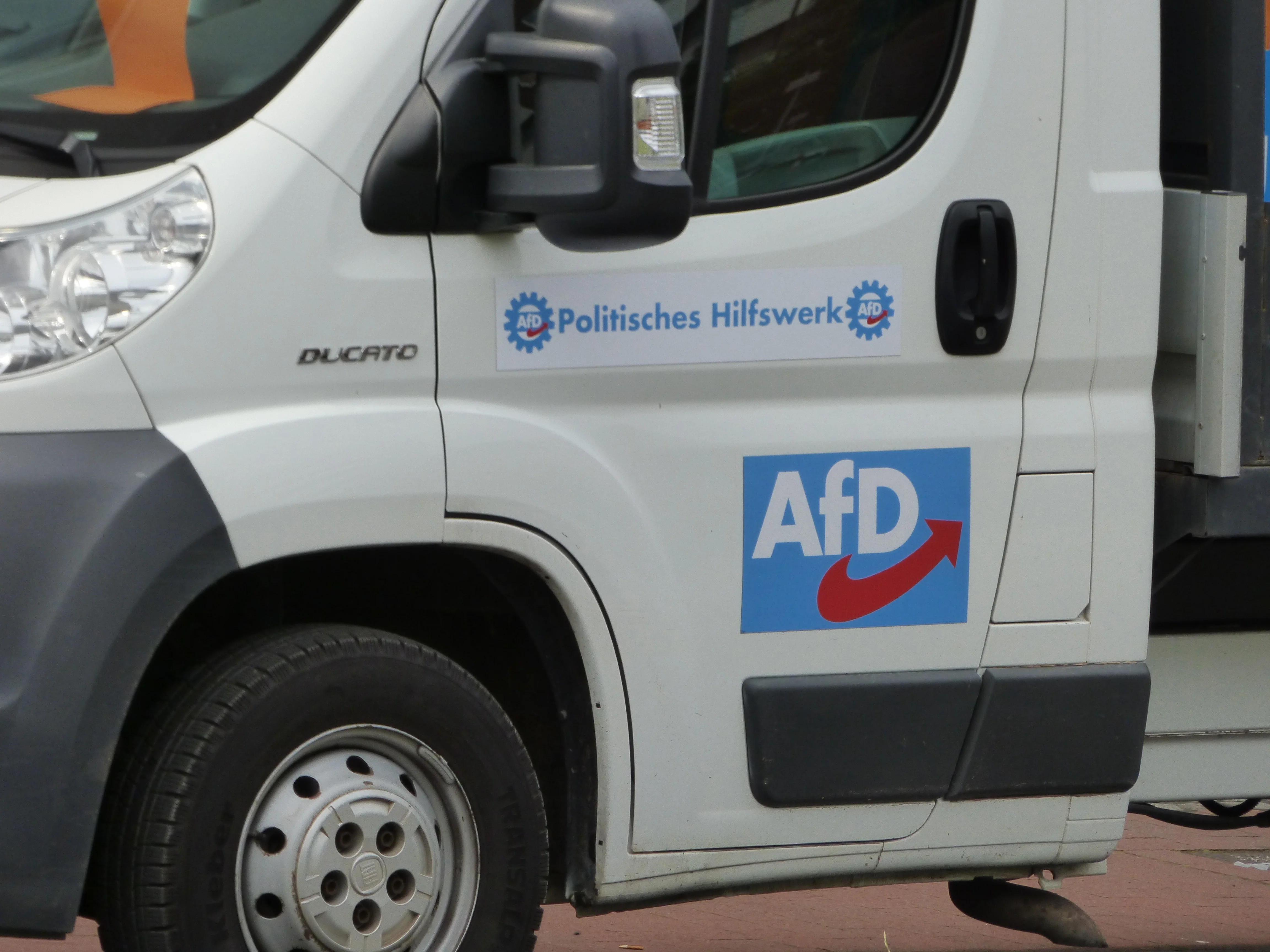 Tür des AfD-Transporters mit der Aufschrift Politisches Hilfswerk, Zahnradmotiven und AfD-Logo.