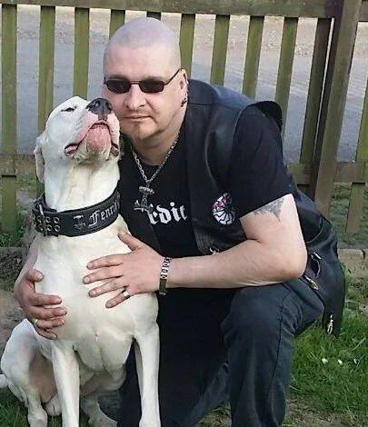 Im ursprünglichen Beitrag Lars H. zugeordnetes Foto: ein Mann in einer schwarzen Weste mit Aufnäher neben einem Hund.