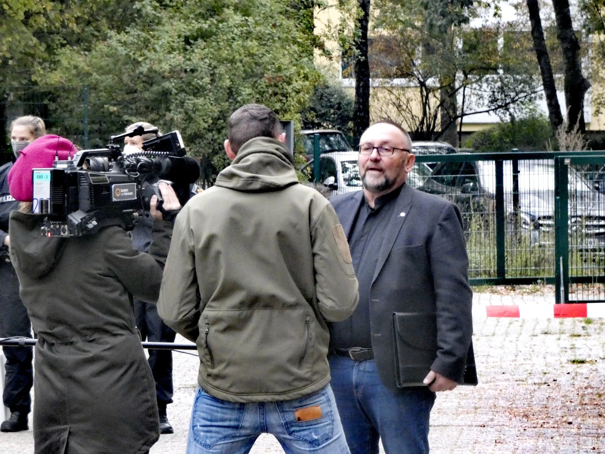 Frank Magnitz spricht vor dem Tagungsort mit einem Fernsehteam; auf der Kamera ist das Logo von buten un binnen erkennbar.
